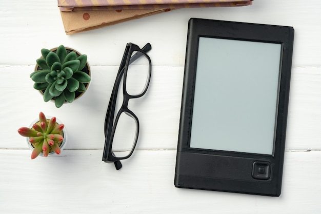 Portable ebook reader on wooden background top view