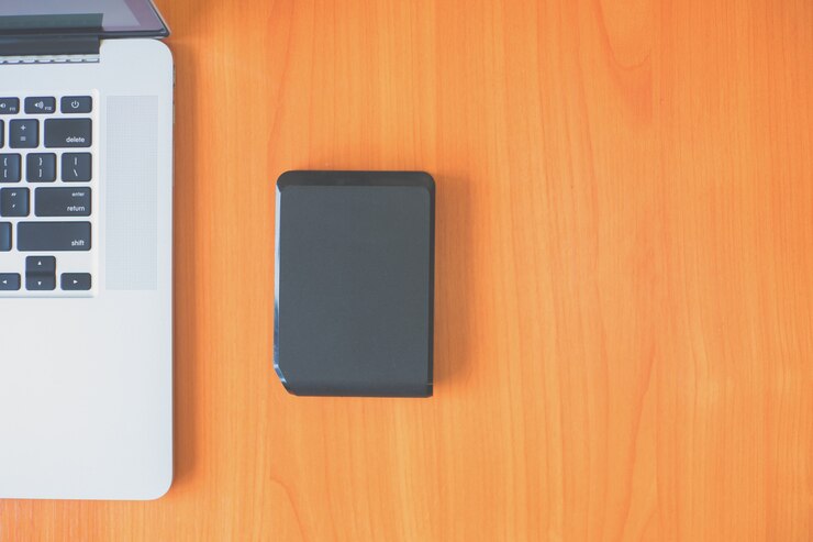 Portable external hard drive on the desk near the laptop
