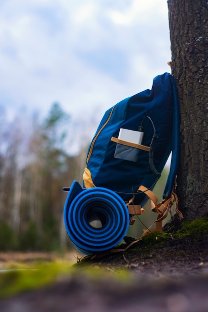 Portable travel charger. Power Bank charges Smartphone against a backdrop of journey bags and forest. Concept on the theme of tourism.