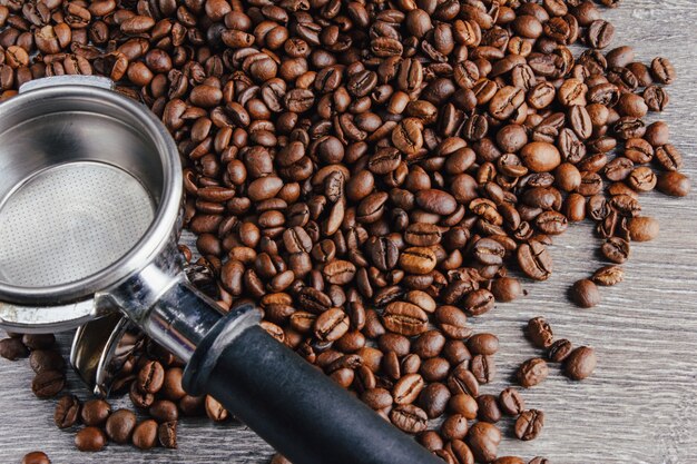 Foto portafiltro e chicchi di caffè su fondo di legno