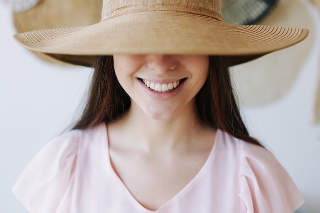 портрет красивой молодой улыбающейся женщины в летней шляпе