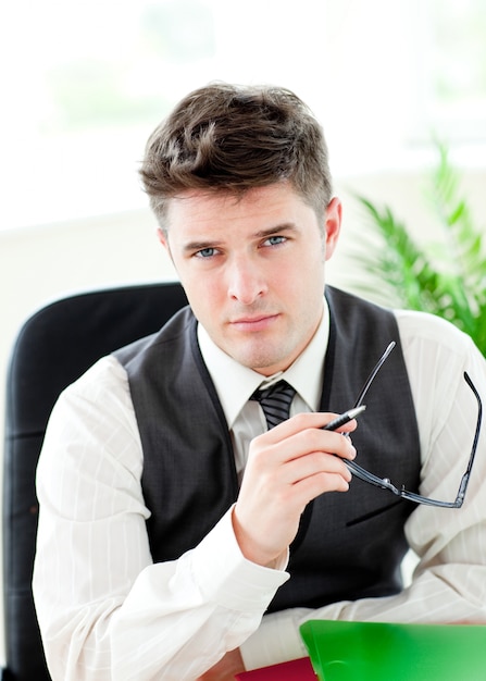 Portait of a self-assured businessman holding glasses 