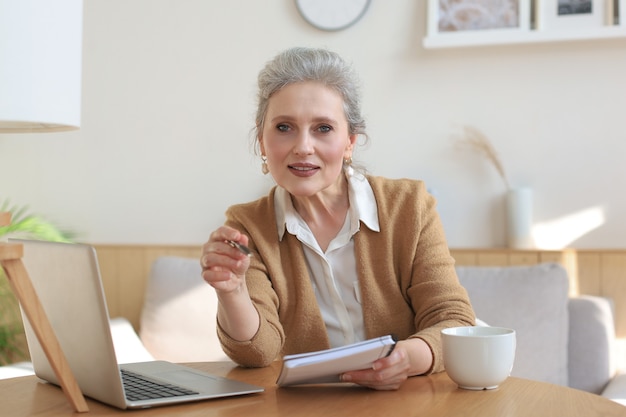 Portait of smiling beautiful middle aged woman looking at camera, making video call, job interview or online dating.