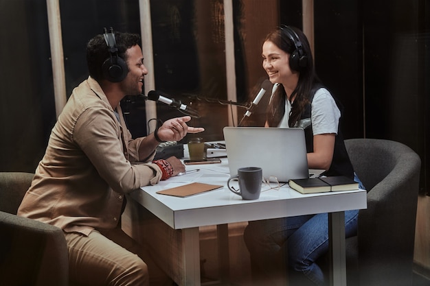 Portait of two happy radio hosts young man and woman smiling while discussing various topics