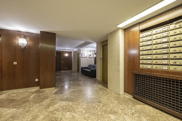 Portal of a residential building with walls covered in wood brass mailboxes courtesy sofas and several elevators