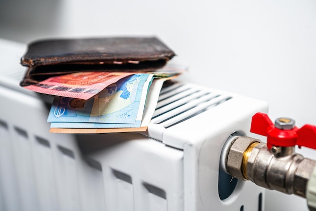 Portemonnee met eurobankbiljetten op het concept van de radiator van de centrale verwarming van dure verwarmingskosten close-up
