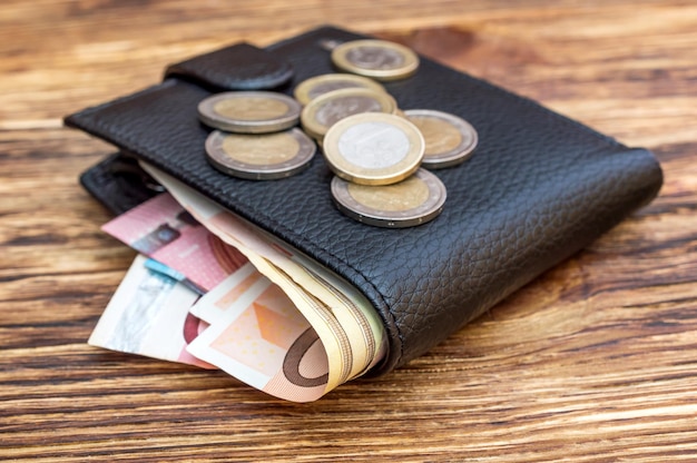 Portemonnee met eurobiljetten en euromunten op houten tafel Bedrijfsconcept