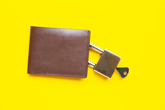 Portemonnee met hangslot en sleutel op gele tafel. Kopieer ruimte
