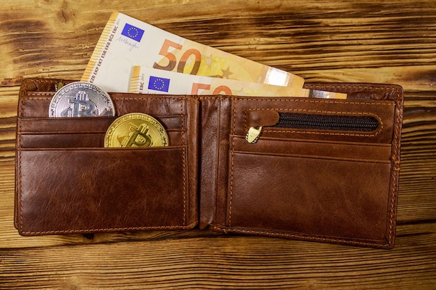 Foto portemonnee met vijftig euro rekeningen en bitcoins op houten achtergrond