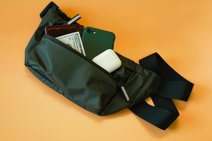 Portemonneetelefoon 100 dollar en witte draadloze koptelefoon in een kaki heuptasje ligt op een gele achtergrond Oranje kleding 100 dollar Private Security Zip Design Wear Personal Fabric One