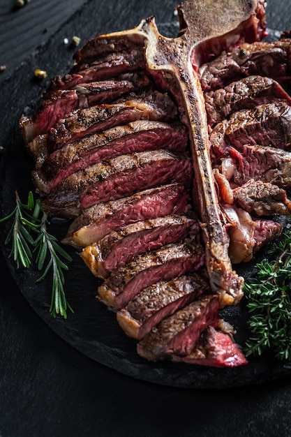 Porterhouse steak is grilled sliced on a piece. grilled large t-bone steak garnished. Food recipe background. Close up. vertical image.