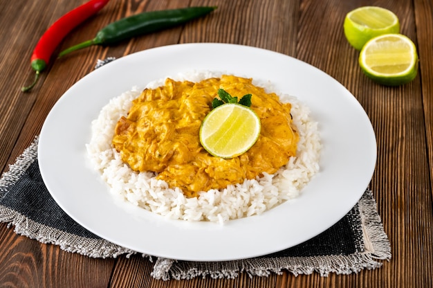 Portie kipcurry gegarneerd met rijst en verse limoen