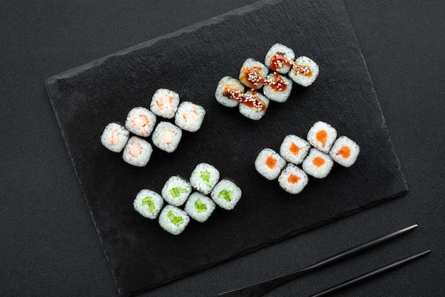 Portie klassieke verse sushirolletjes met nori, zalm, komkommer, gerookte paling