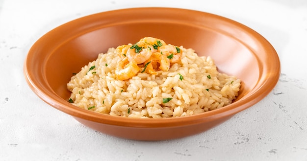 Portie risotto gegarneerd met garnalen in de kom