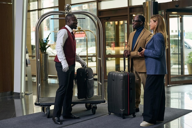 Portier met trolley die bagage van gasten in het hotel meeneemt tijdens het inchecken