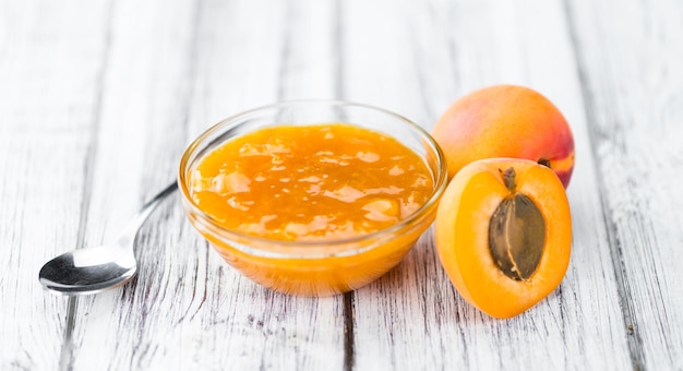 Photo portion of apricot jam on wooden background selective focus