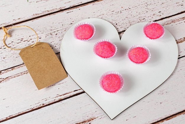 Portion of bicho de pe on a wooden board in the shape of a heart. beside a brown tag.