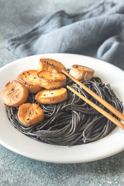 Photo portion of black pasta with king oyster scallops