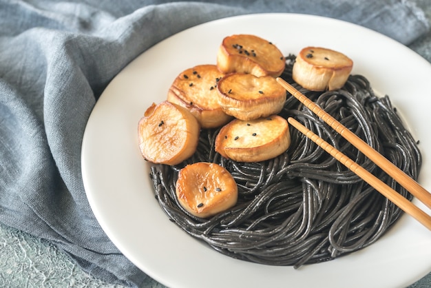 Photo portion of black pasta with king oyster scallops