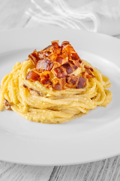 Portion of carbonara pasta garnished with fried guanciale