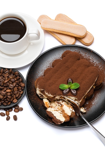 Portion of Classic tiramisu dessert, savoiardi cookies and cup of fresh espresso coffee isolated on white background