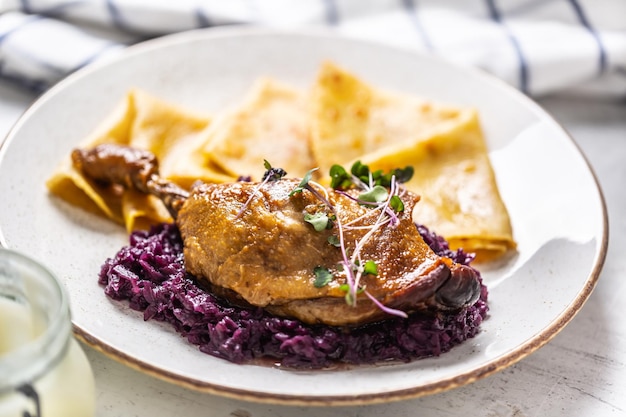 Portion of duck leg with red cabbage and potato pancakes, a traditional autumn dish in Eastern Europe.