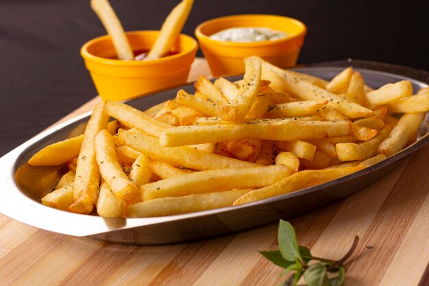 Porzione di patatine fritte in una ciotola d'argento sopra una tavola di legno con tessuto a scacchi