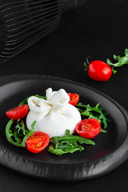 Porzione di caprino fresco bianco con burrata con rucola e pomodorini