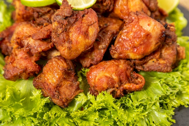 Portion of fried chicken on black stone plate.