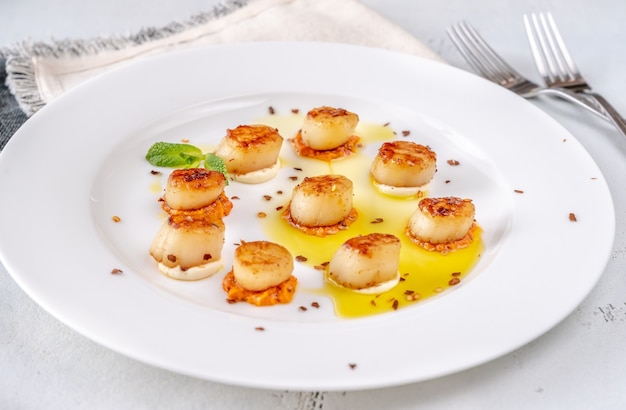 Portion of fried scallops with cauliflower puree and orange pesto sauce