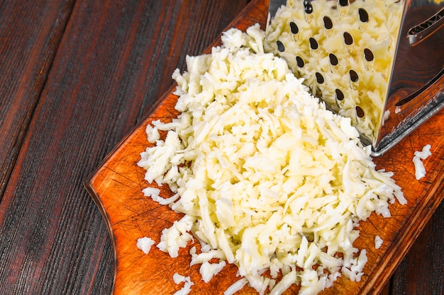 소박한 나무 테이블에 강판 된 체 다 치즈의 부분.