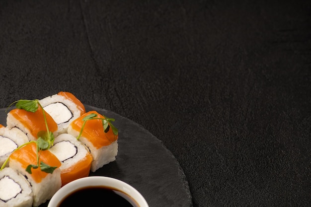 Portion of japanese sushi philadelphia on a stone plate on a\
black background