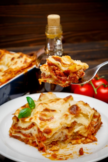 Foto porzione di primo piano delle lasagne al forno su backgound di legno