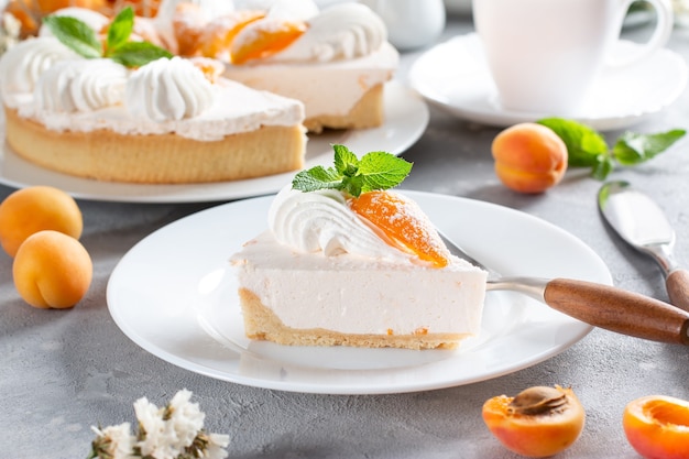 Portion of layered cheesecake with apricot on light background. Apricot tart. Fruit pie. French pastries.