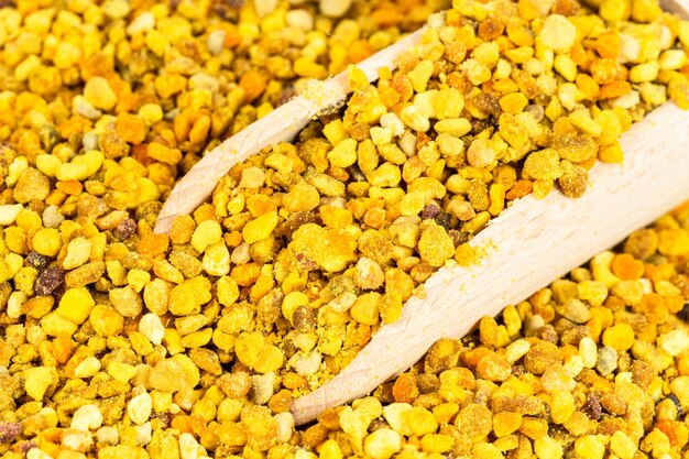 Portion of natural bee pollen in wooden scoop