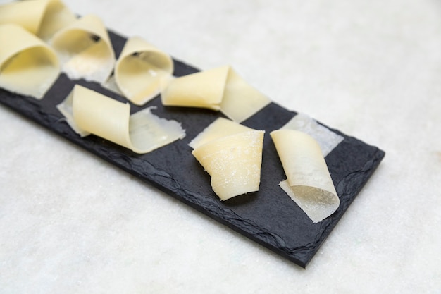 Portion of parmesan cheese in flakes with balsamic vinegar in black stone