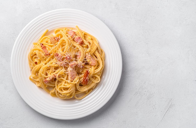 A portion of pasta carbonara with bacon parmesan cheese and egg on a light gray background Top view copy space