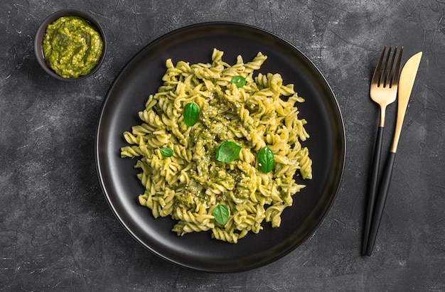 A portion of pasta with basil pesto sauce on a dark background Top view horizontal