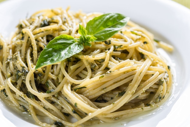 Portion of pasta with pesto sauce and basil leaf