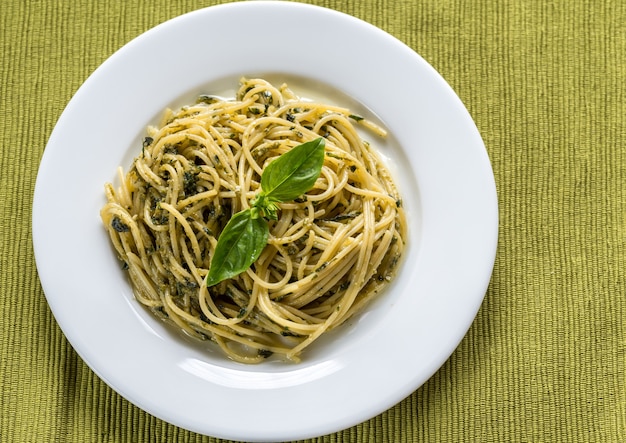 Portion of pasta with pesto sauce and basil leaf