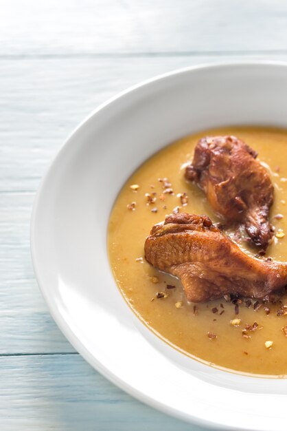 Portion of pea cream soup with smoked chicken wings