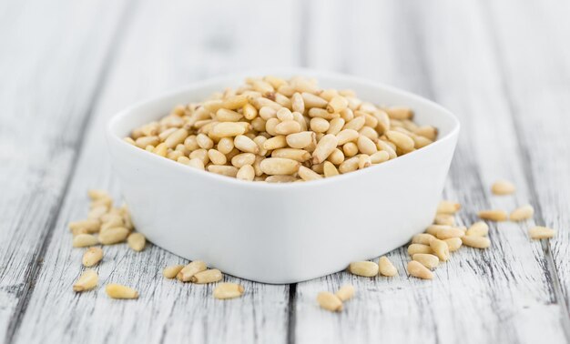 Portion of Pine Nuts on wooden background selective focus