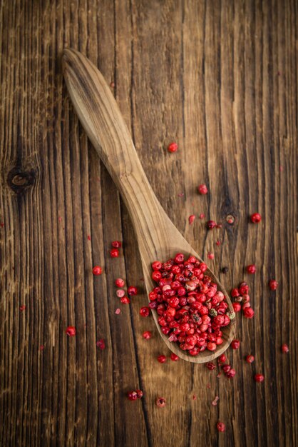 Portion of pink peppercorns on wooden background selective focus