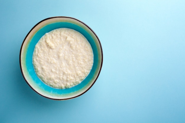 Portion of rice porridge in bowl on blue background, close-up, top view, view from above, lay out, flat lay, copy space