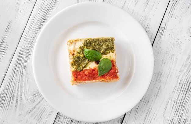 Portion of ricotta lasagne topped with tomato sauce and pesto