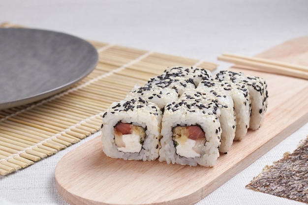 Una porzione di panini su un supporto, cibo giapponese, sushi sul tavolo, bacchette cinesi, sfondo chiaro