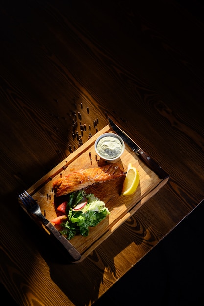 Porzione di filetto di salmone con erbe su un tavolo di legno. vista dall'alto