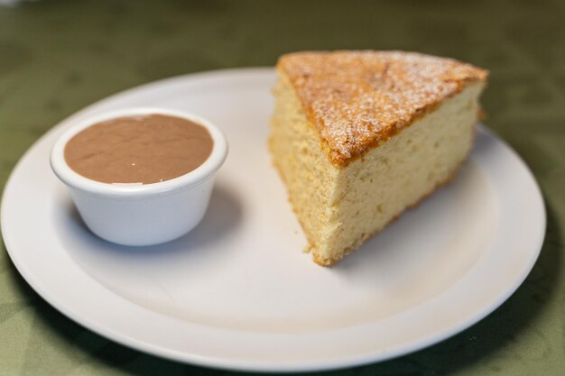 Portion of santiago cake served with chocolate sauce in a white ceramic dish in a restaurant