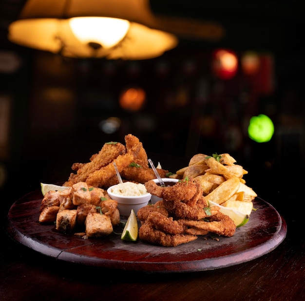 portion of seafood with breaded fish and shrimp and grilled salmon with french fries blurred background