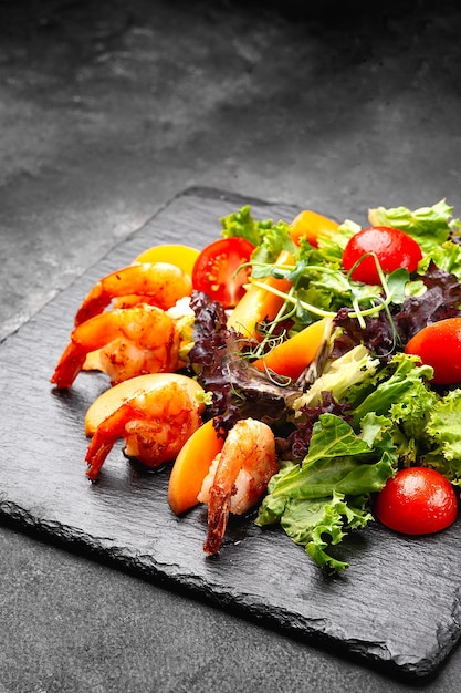 Portion of shrimp and vegetable salad on a black plate